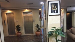 A lobby with two elevators, potted plants, a framed artwork, and a couch. - Ahla Tlah SeaView Hotel (Aqaba)