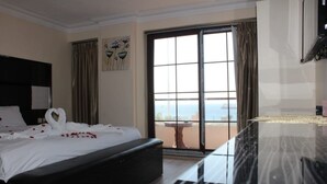 A hotel room with a large bed, a balcony with a view, and a dining area. - Ahla Tlah SeaView Hotel (Aqaba)