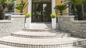 Un bâtiment doté d’une entrée centrale, d’un escalier en pierre et de plantes en pot.