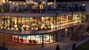 Un hotel de varios pisos con piscina, mobiliario exterior y una terraza techada.