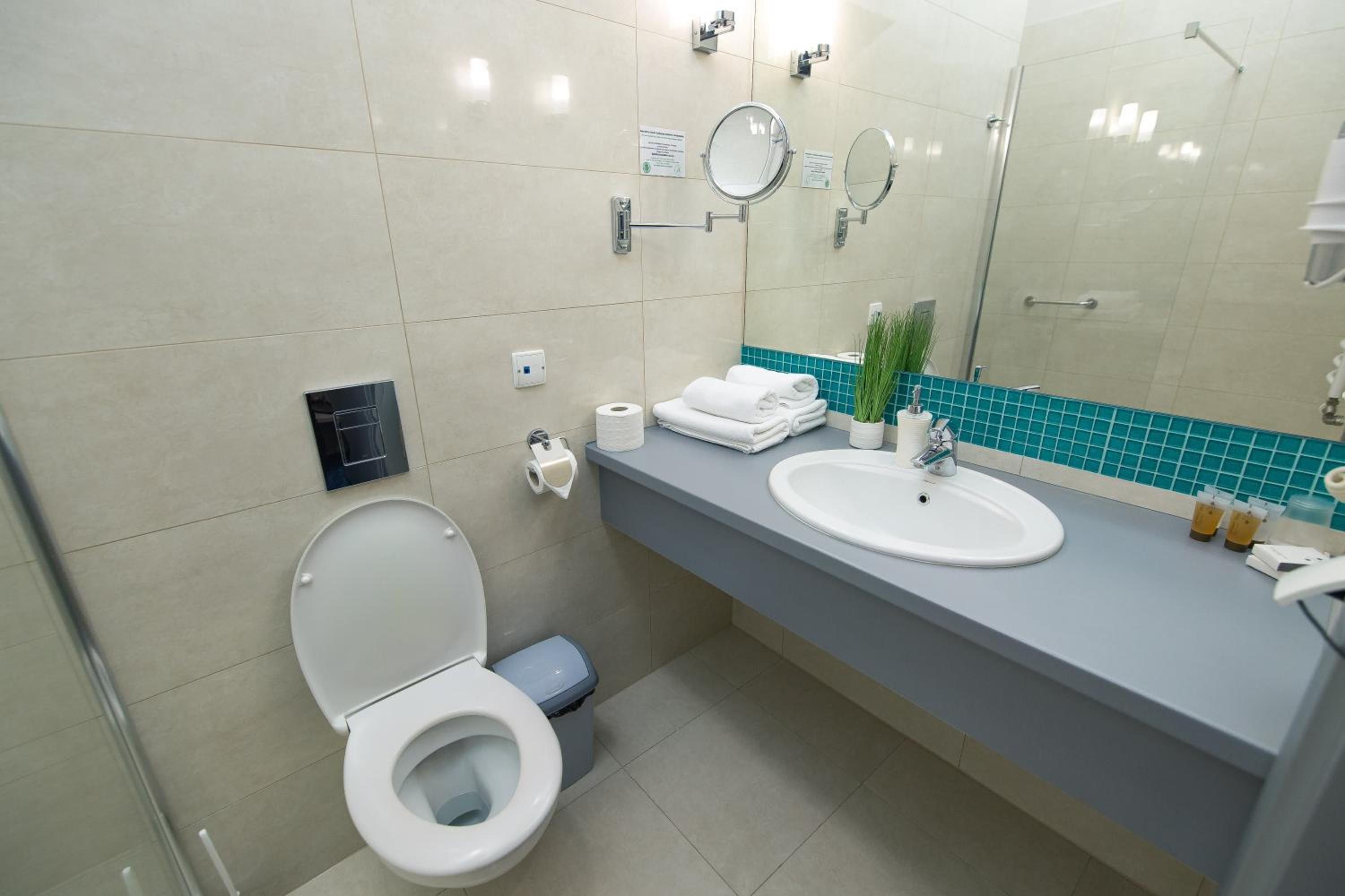A modern bathroom with a toilet, sink, and mirrors.