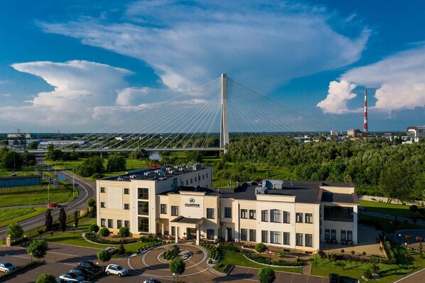 A modern building complex with a prominent cable-stayed bridge in the background.