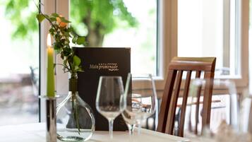 A dining table set with wine glasses, a candle, and a menu.
