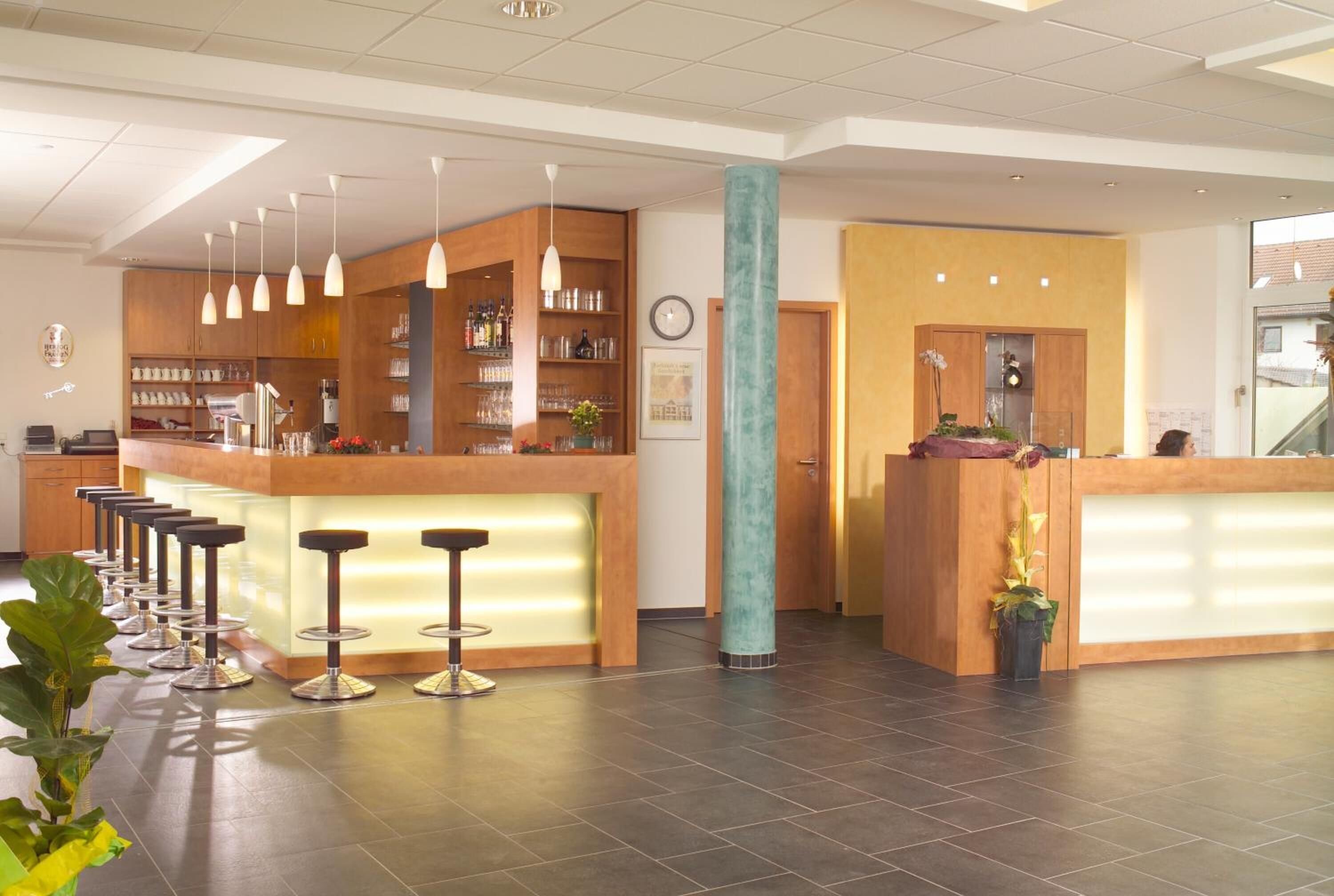 Un lobby moderno de hotel con mostrador de recepción, zona de bar y asientos.