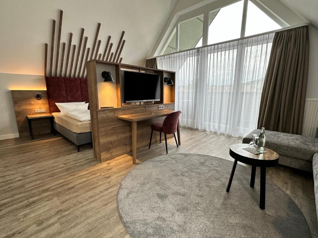 Una habitación de hotel moderna con cama, escritorio, televisor y zona de estar.