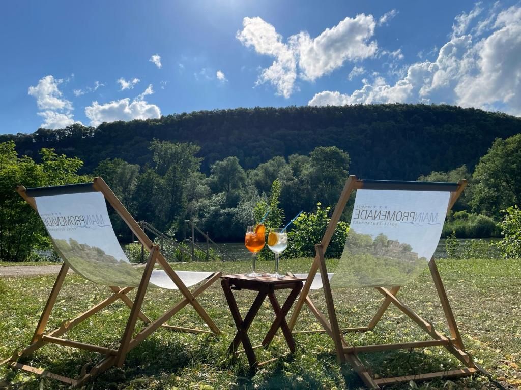 Zwei hölzerne Stühle mit einem Tisch dazwischen, ein Glas mit einem Getränk und ein Schild mit Text.