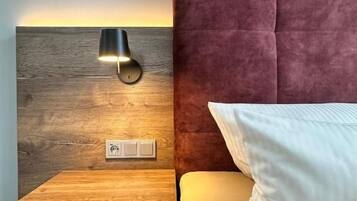 A bed with a headboard, a bedside table, and a wall-mounted lamp.