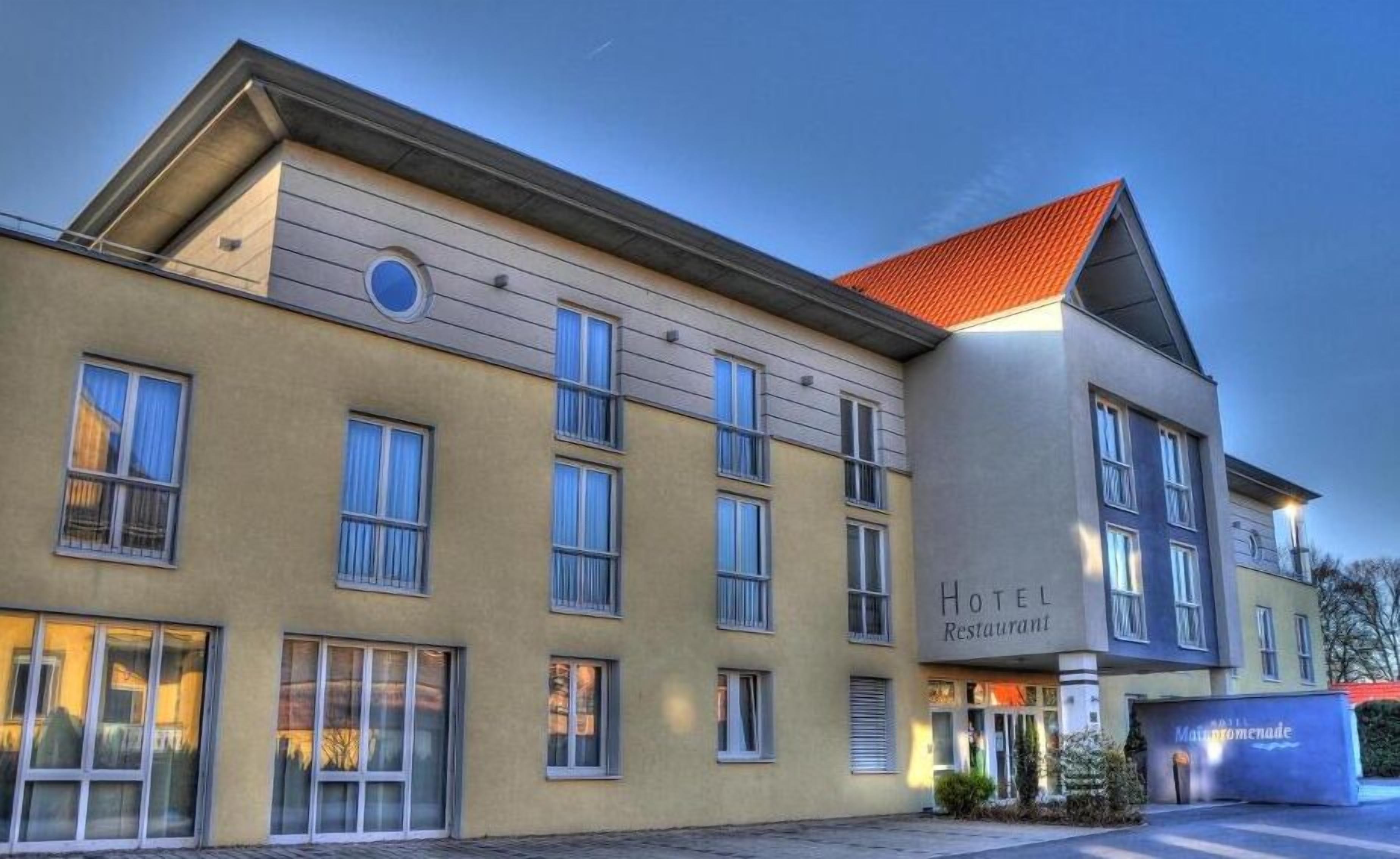 A hotel building with multiple windows, a prominent entrance, and a sign indicating it is a hotel and restaurant.