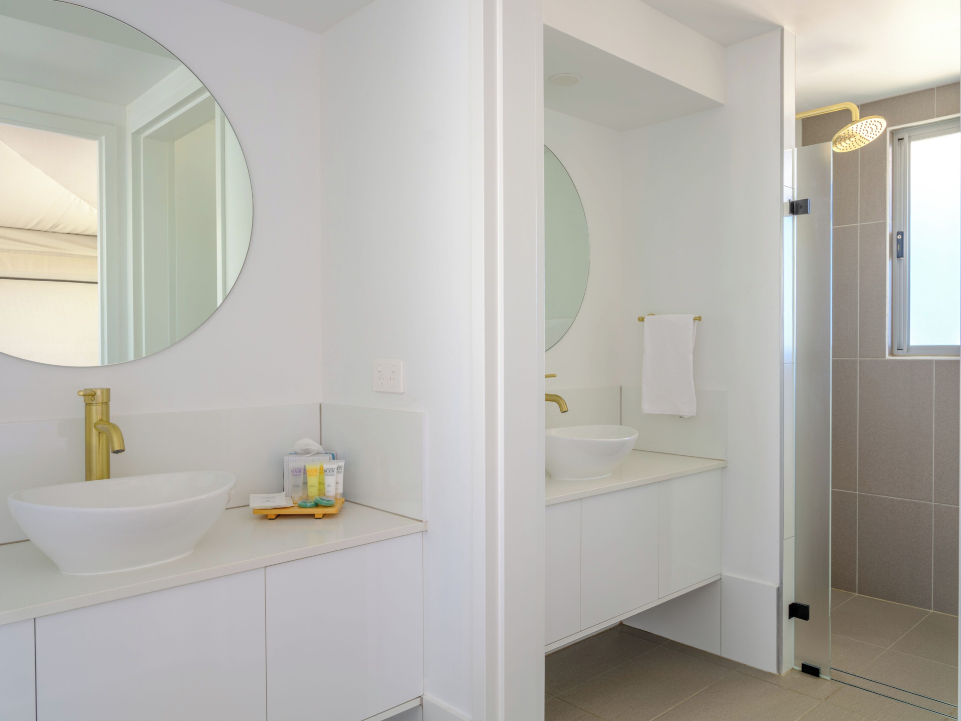 Un bagno moderno con due lavandini, uno specchio grande e una zona doccia.