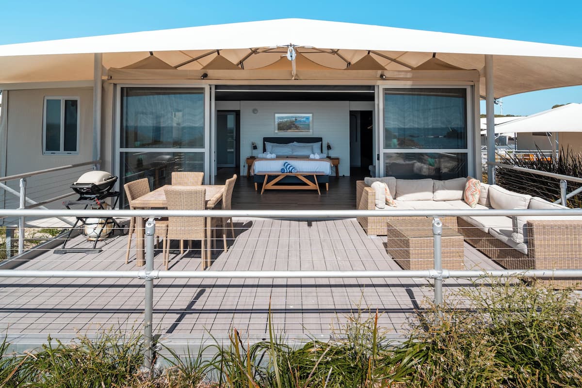 A modern outdoor living space with a covered patio, a bed, and a seating area.