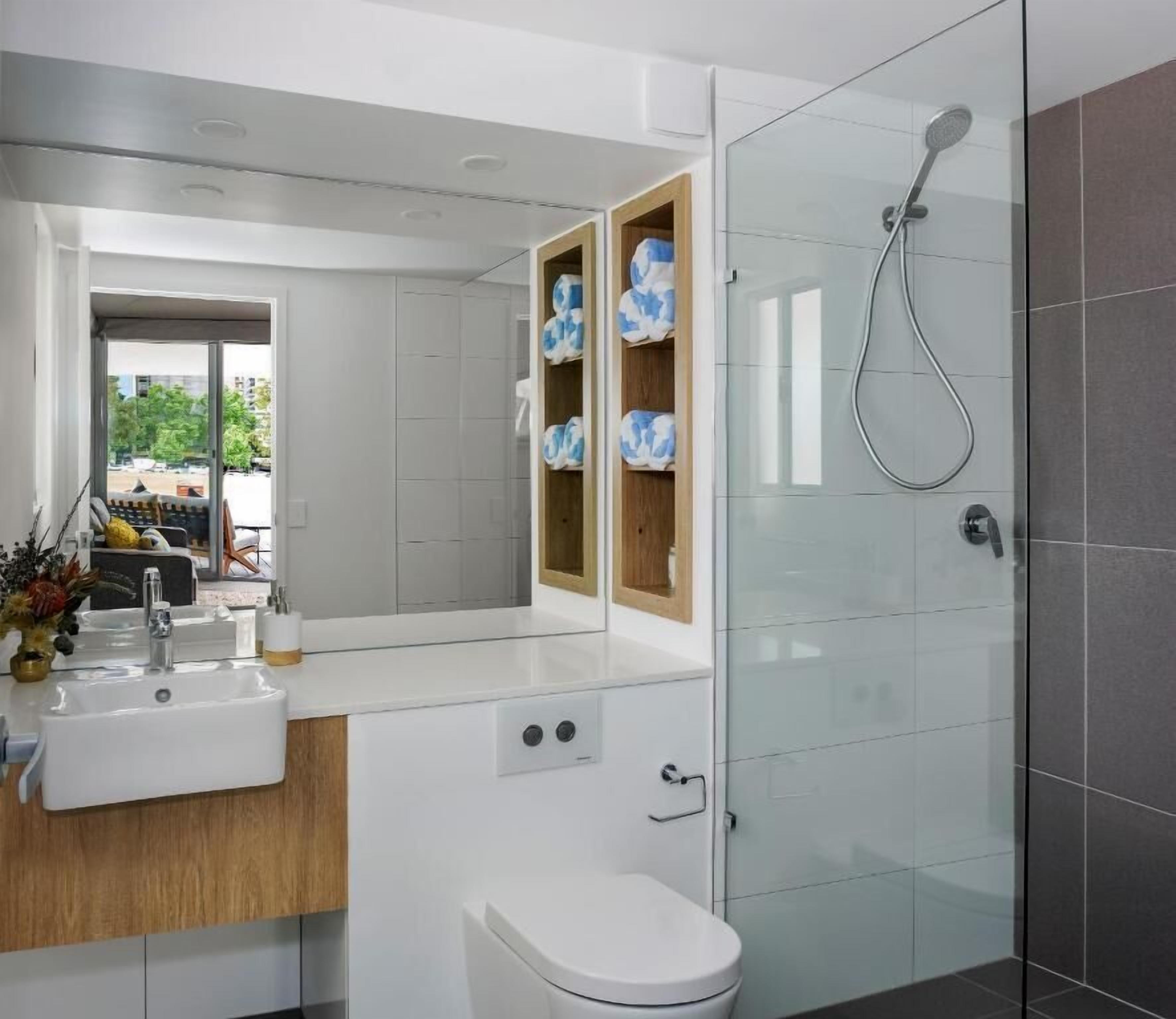 A modern bathroom with a glass shower enclosure, a white sink, and a toilet.