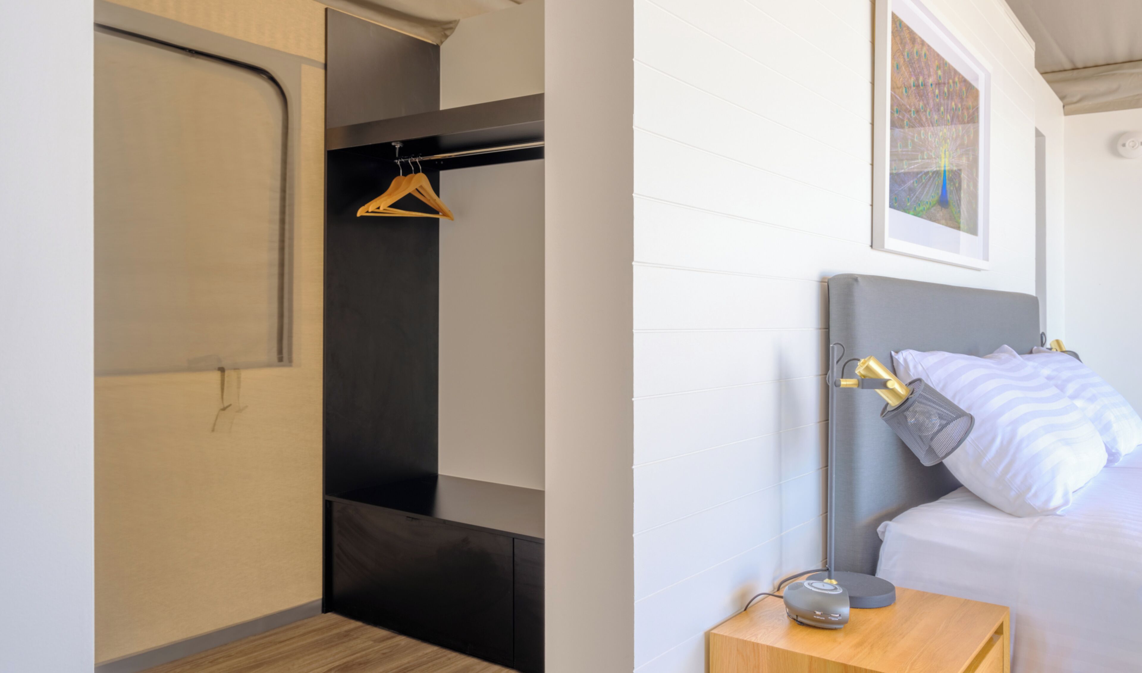 A modern bedroom with a bed, bedside table, and a hanging closet.