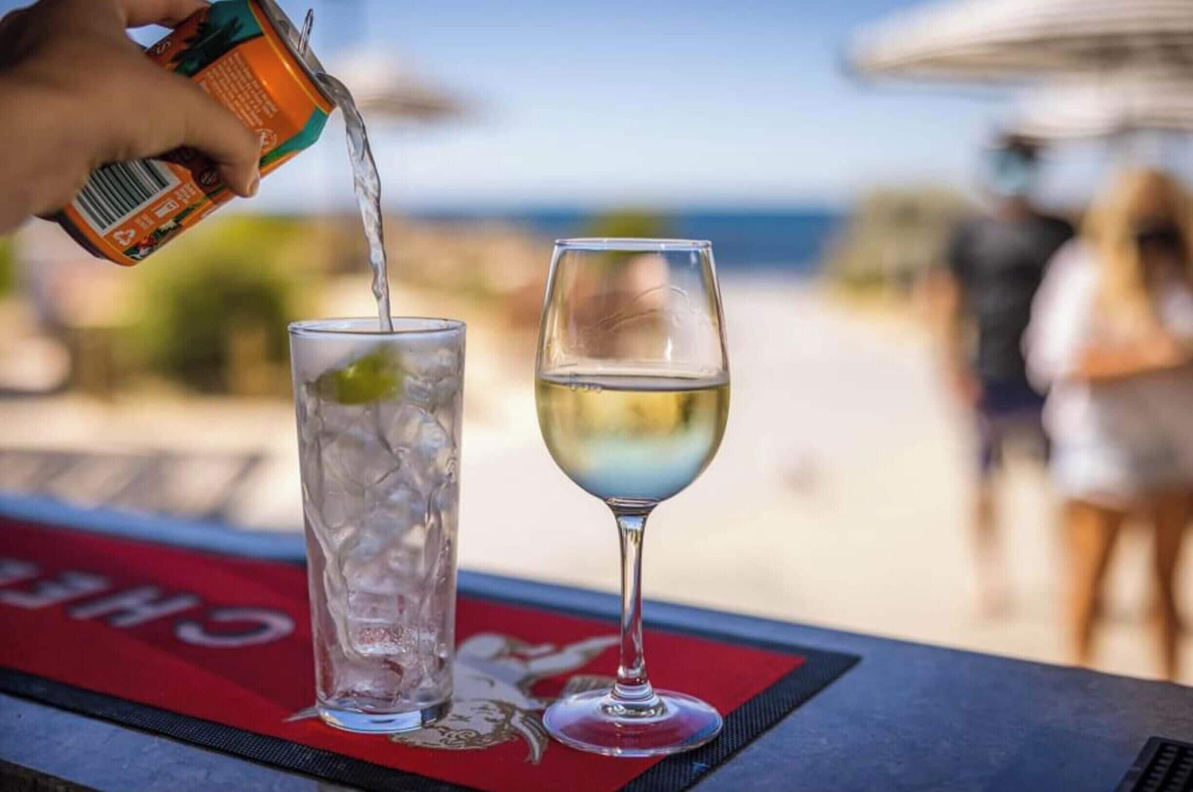 A person pouring a drink into a glass on a table with a red placemat.