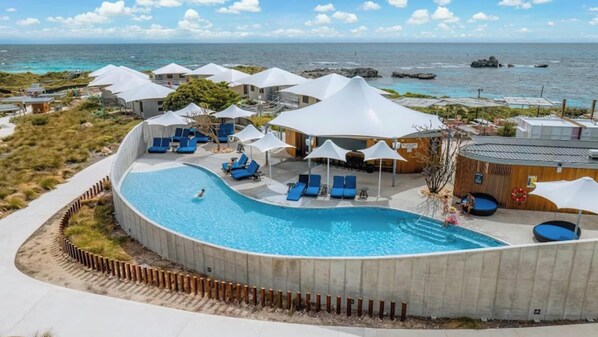 Una piscina al aire libre, sillones reclinables de piscina