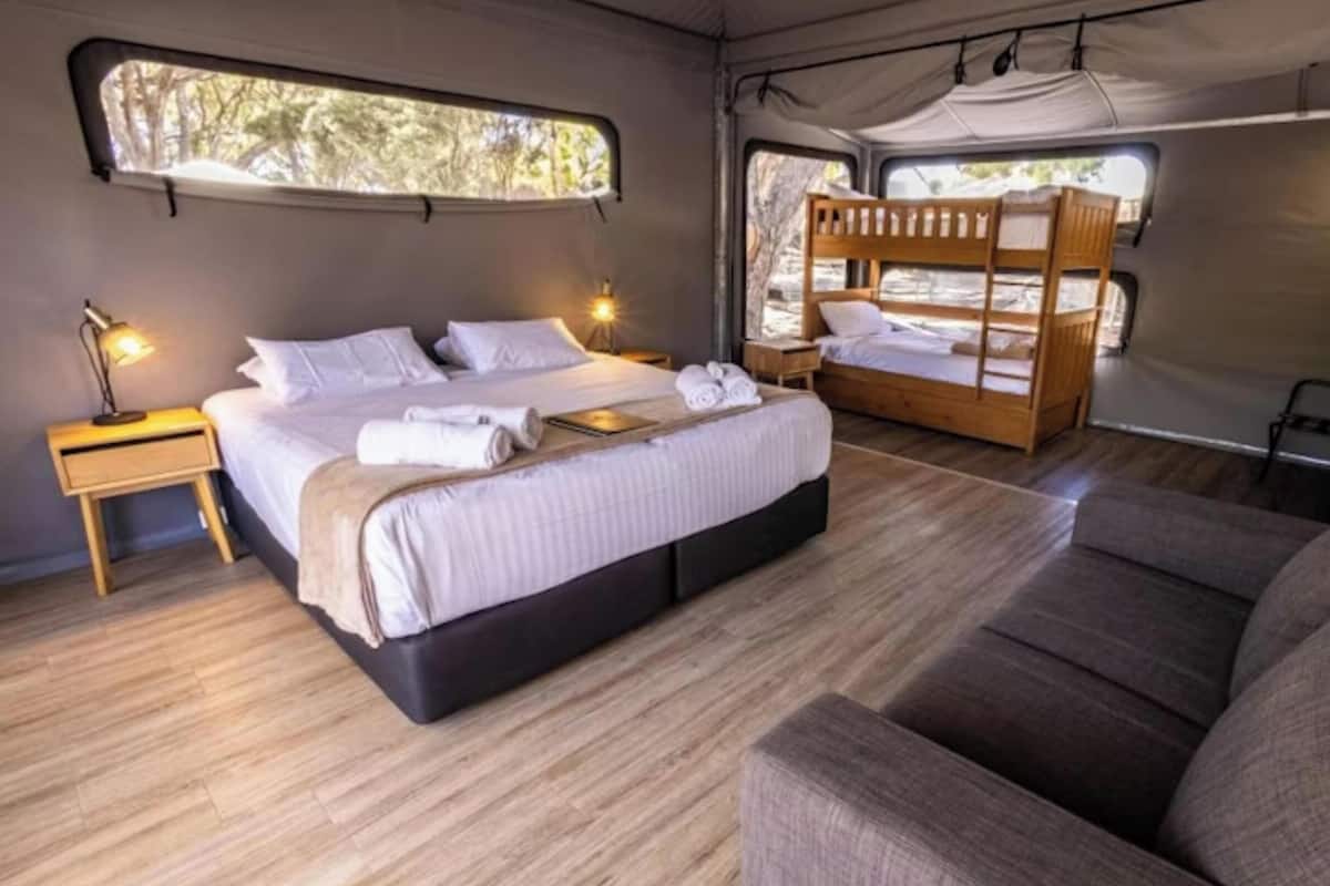 A compact bedroom with a single bed, a small bedside table, and a bench.