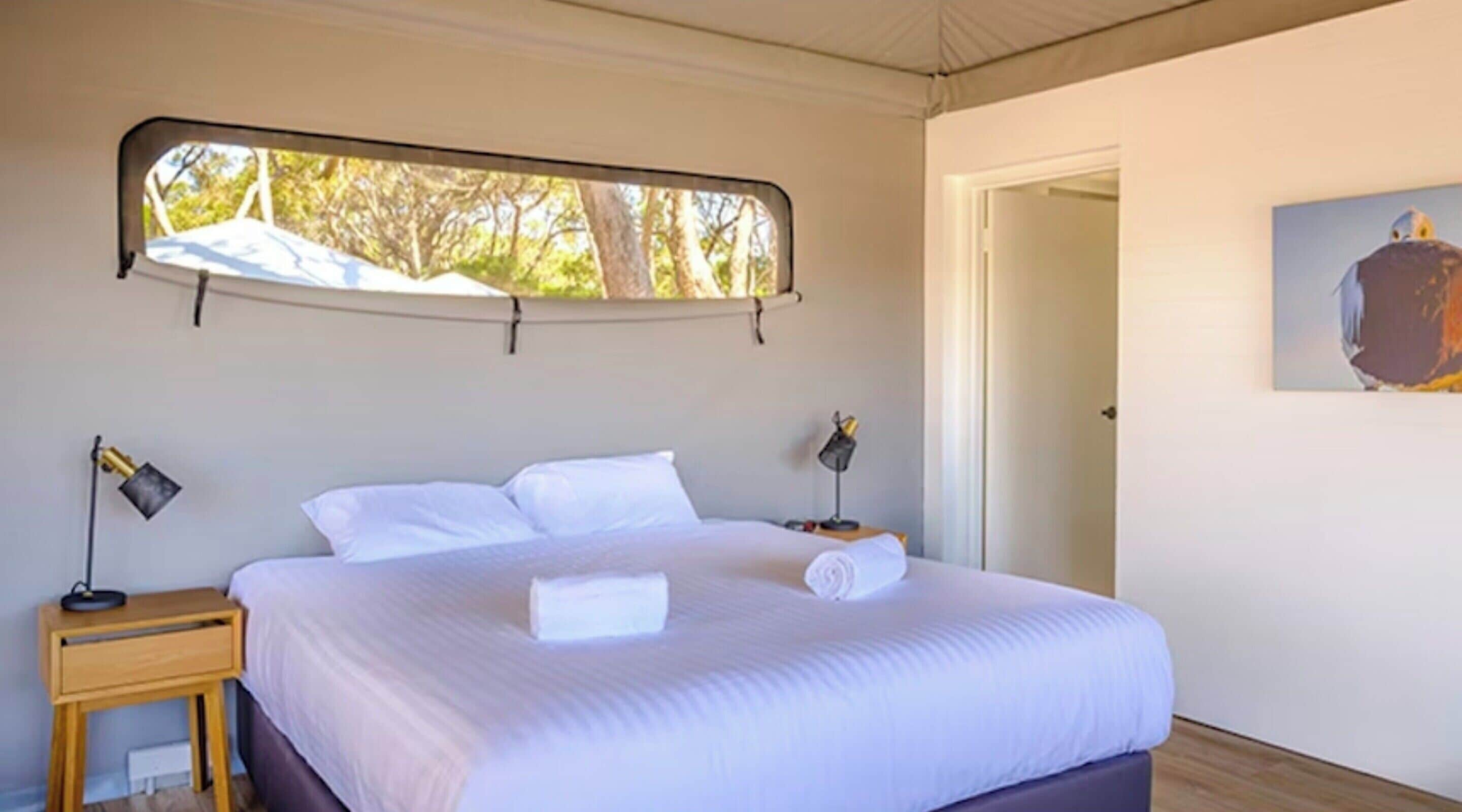 Un dormitorio con una cama, dos lámparas de noche, una ventana y una puerta.