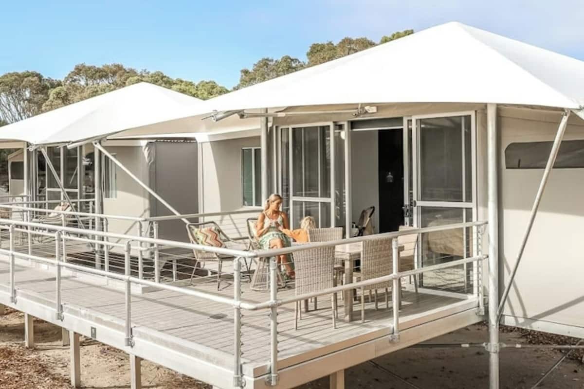 A series of white tents with a covered walkway and seating area.