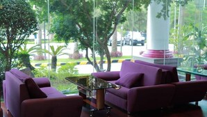 Un interior moderno con sofás morados, una mesa de centro de vidrio y vistas a zonas verdes y un monumento exterior.