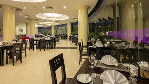 Un restaurante espacioso con varias mesas y sillas, un diseño moderno de techo y ventanas amplias.