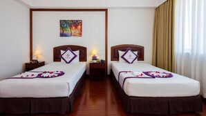 Quarto de hotel com duas camas, um quadro na parede e uma janela com cortinas.