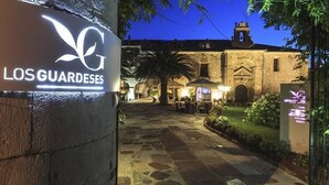 A courtyard with a sign for "Los Guardedes" and a building with a bell tower in the background. - LOS Guardeses (Medio Cudeyo)