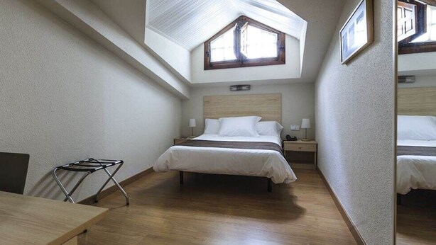 A bedroom with a skylight, a bed, a bedside table, and a chair. - LOS Guardeses (Medio Cudeyo)