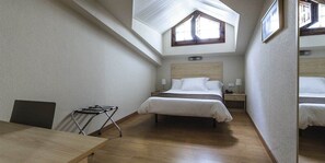 Un dormitorio con tragaluces, una cama, una mesita de noche y una silla.
