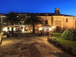 Un patio al aire libre con suelo de piedra, palmeras y zonas de estar exteriores.