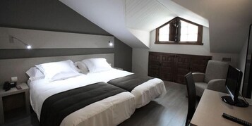 Un dormitorio con cama, mesita de noche y escritorio con ordenador.