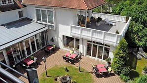 A two-story building with a patio area, outdoor seating, and a garden. - Hotel Restaurant Sengscheider Hof (Sankt Ingbert)