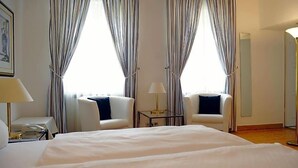 A hotel room with a bed, two chairs, a small table, a lamp, and curtains. - Hotel Restaurant Sengscheider Hof (Sankt Ingbert)