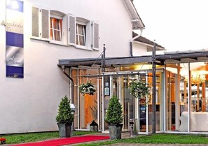 A hotel entrance with a red carpet, hanging flower baskets, and potted plants. - Hotel Restaurant Sengscheider Hof (Sankt Ingbert)
