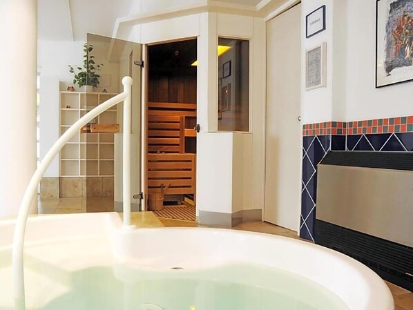 A bathroom with a bathtub, a wooden staircase, and a tiled wall.