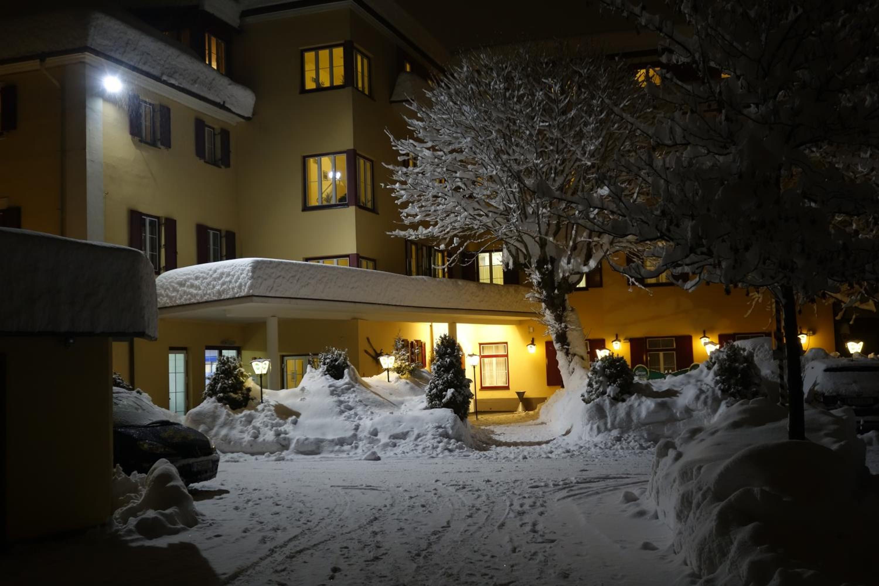 Un hôtel doté d’un espace extérieur abrité, d’arbres couverts de neige et d’un bâtiment avec de nombreuses fenêtres.