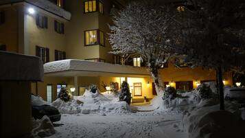 Ein Hotel mit überdachtem Außenbereich, schneebedeckten Bäumen und einem Gebäude mit zahlreichen Fenstern.