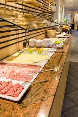 Un buffet proposant une variété de plats, notamment des viandes, des fromages et des fruits.