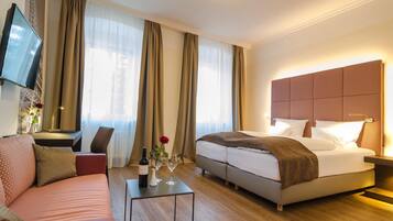 Ein Hotelzimmer mit einem Bett, einem Sofa, einem Fernseher und einem Tisch mit Flasche und Gläsern.