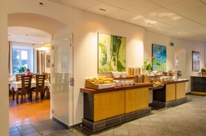 A hotel lobby with a buffet area, dining tables, and artwork on the walls.