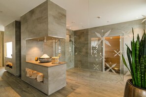 A modern bathroom with a glass shower enclosure, a built-in sink, and a large potted plant.