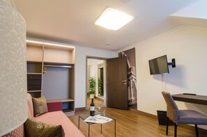A modern living room with a sofa, a coffee table, a TV mounted on the wall, and a wooden floor.