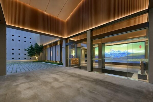 Un bâtiment moderne doté d’un vaste hall d’entrée, d’une façade en verre et offrant une vue sur un paysage montagneux.