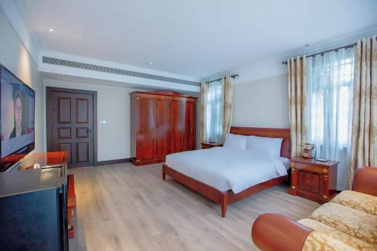 Una habitación de hotel con una cama de madera, un escritorio, un armario y un televisor.