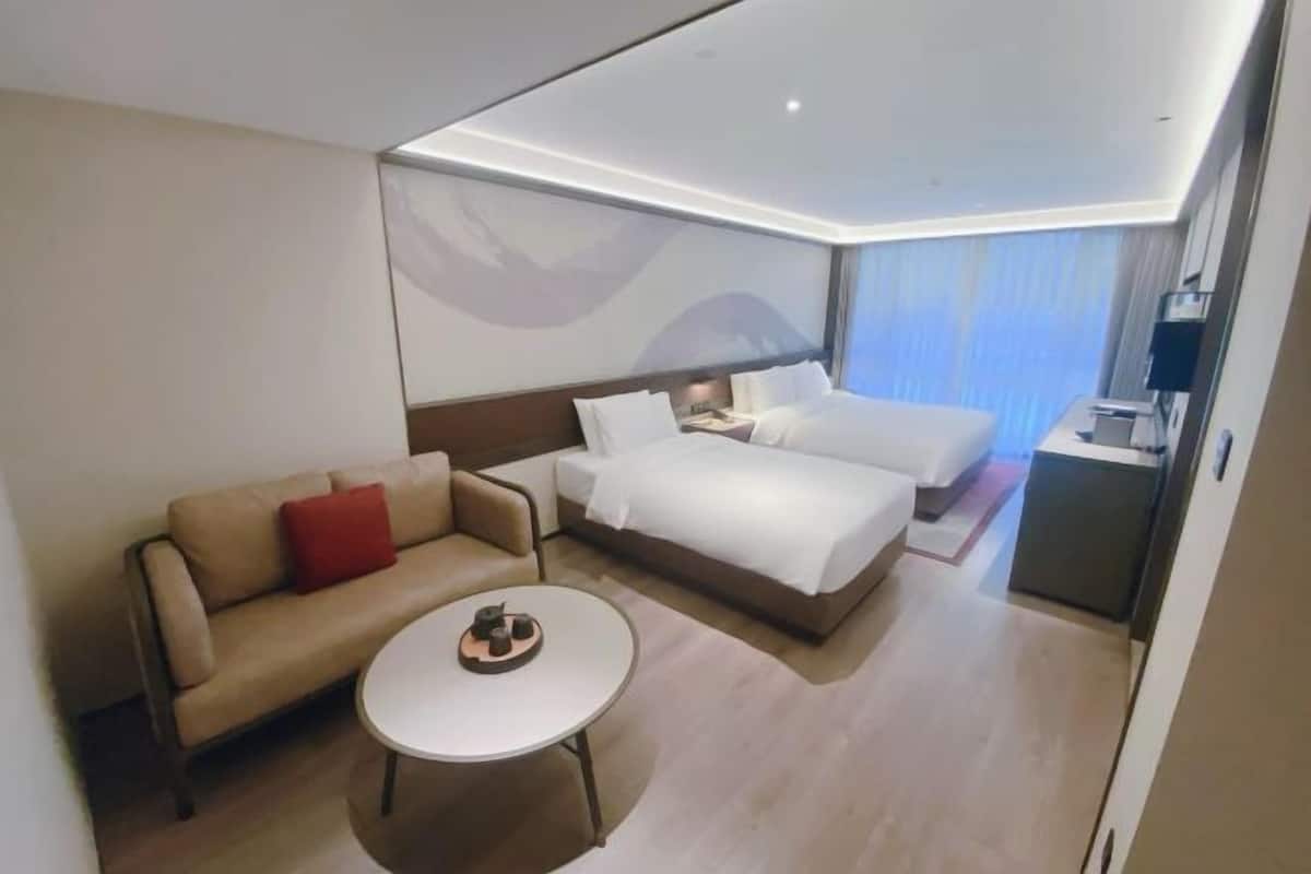 Una habitación de hotel con una cama, un sofá, una mesita y un escritorio.