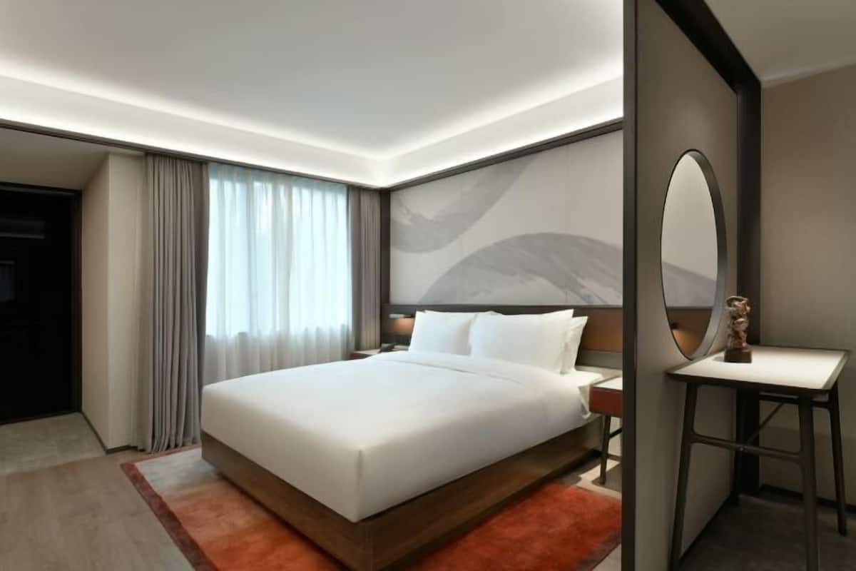 Una habitación de hotel moderna con una cama grande, un escritorio y un espejo.