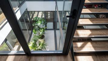 A modern interior with a glass balcony, wooden flooring, and potted plants.