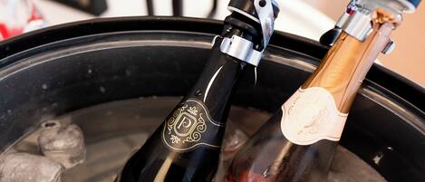Two bottles of wine in a black container with ice cubes.