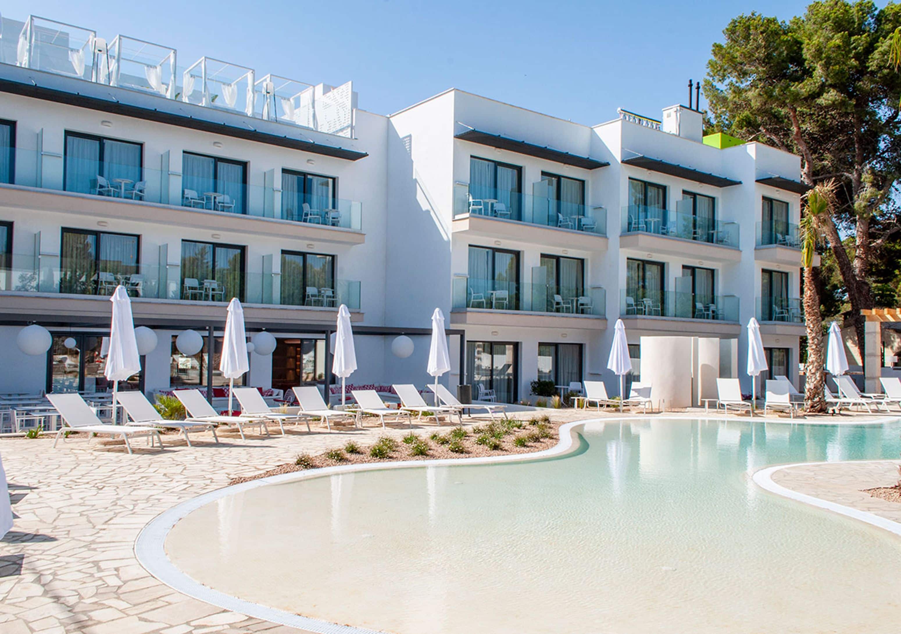 Un hotel moderno con piscina, tumbonas y sombrillas.