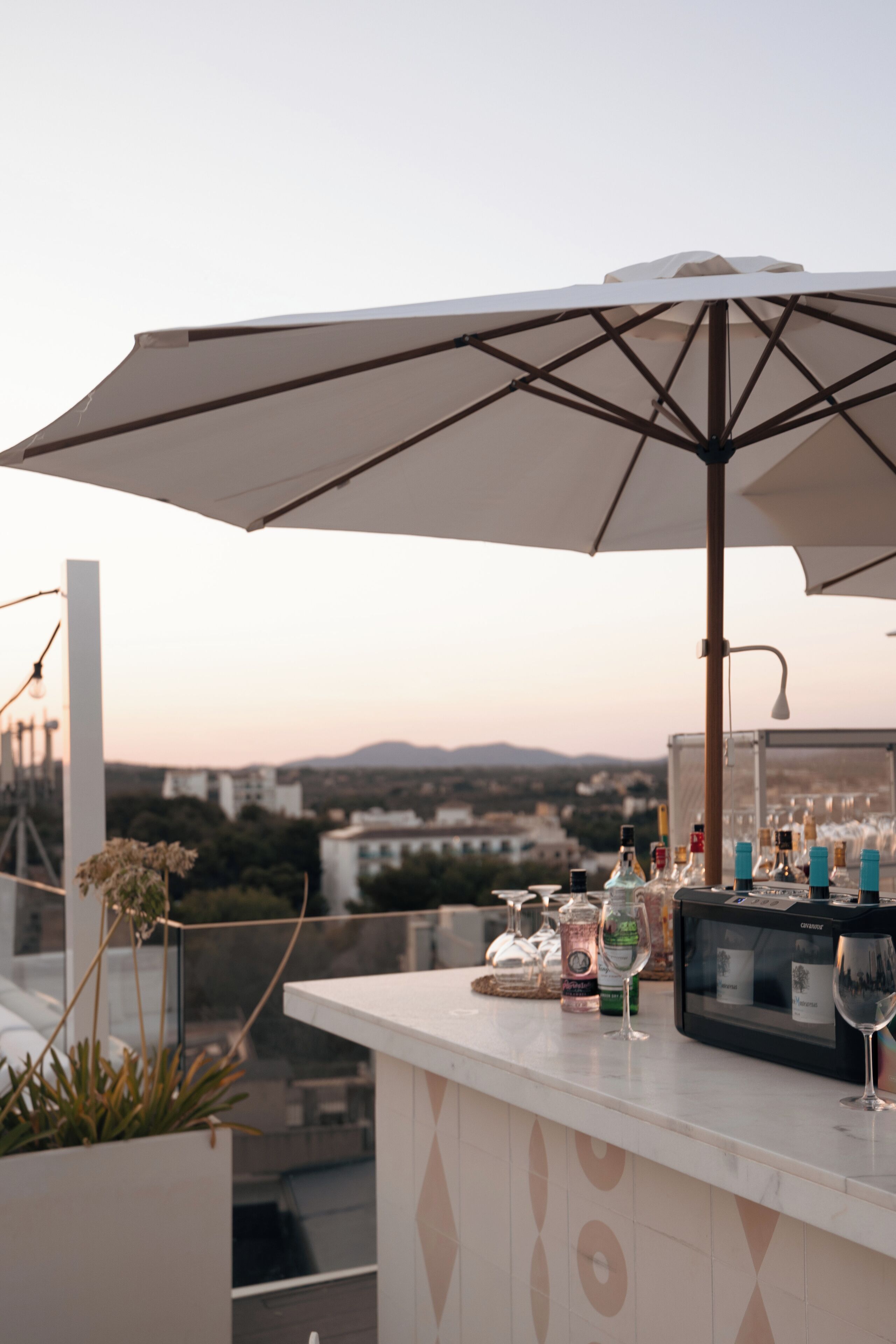 A rooftop bar with an umbrella, bar counter, and bottles.