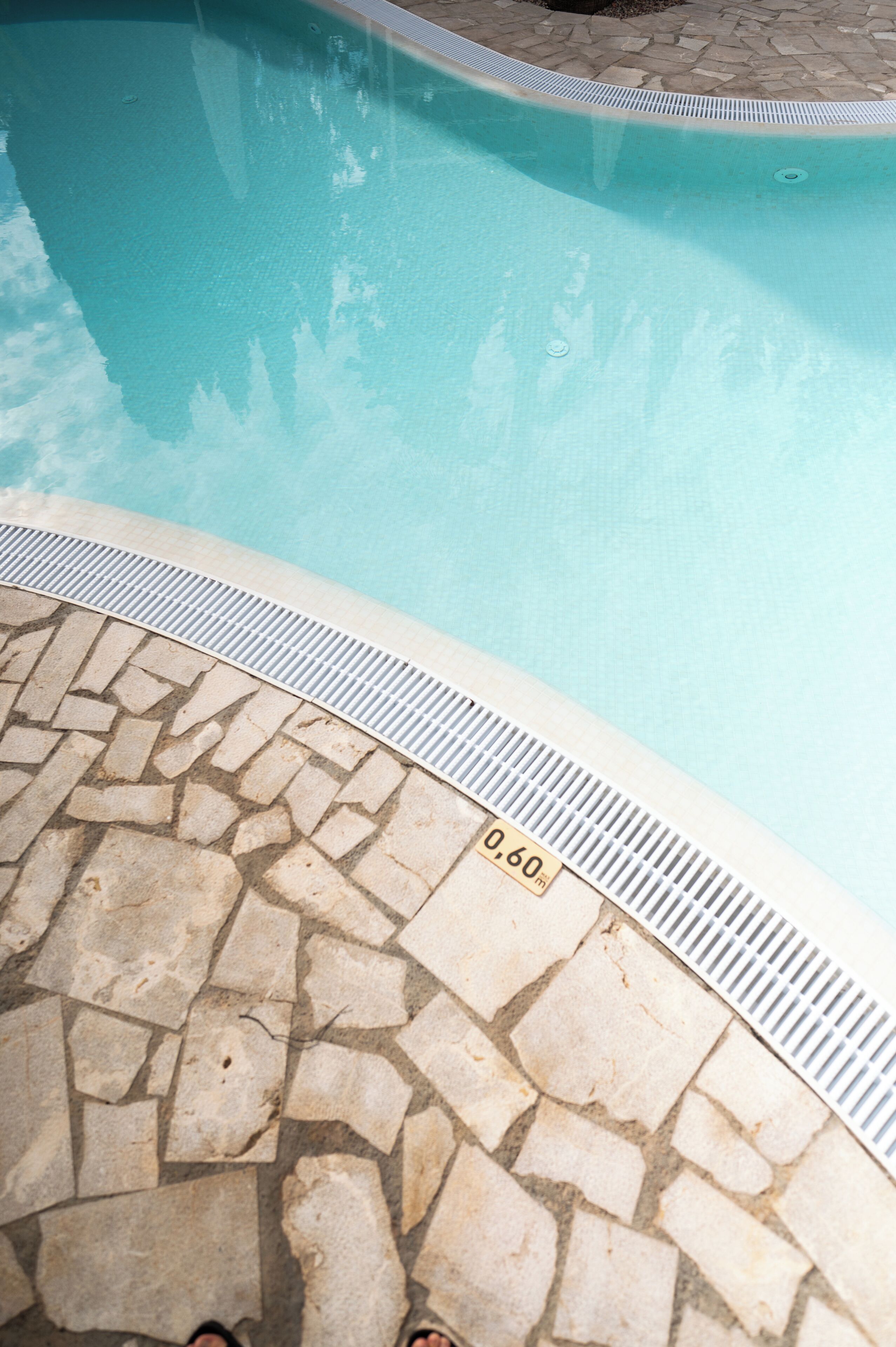 A stone-tiled pool edge with a depth marker indicating 0.60m.