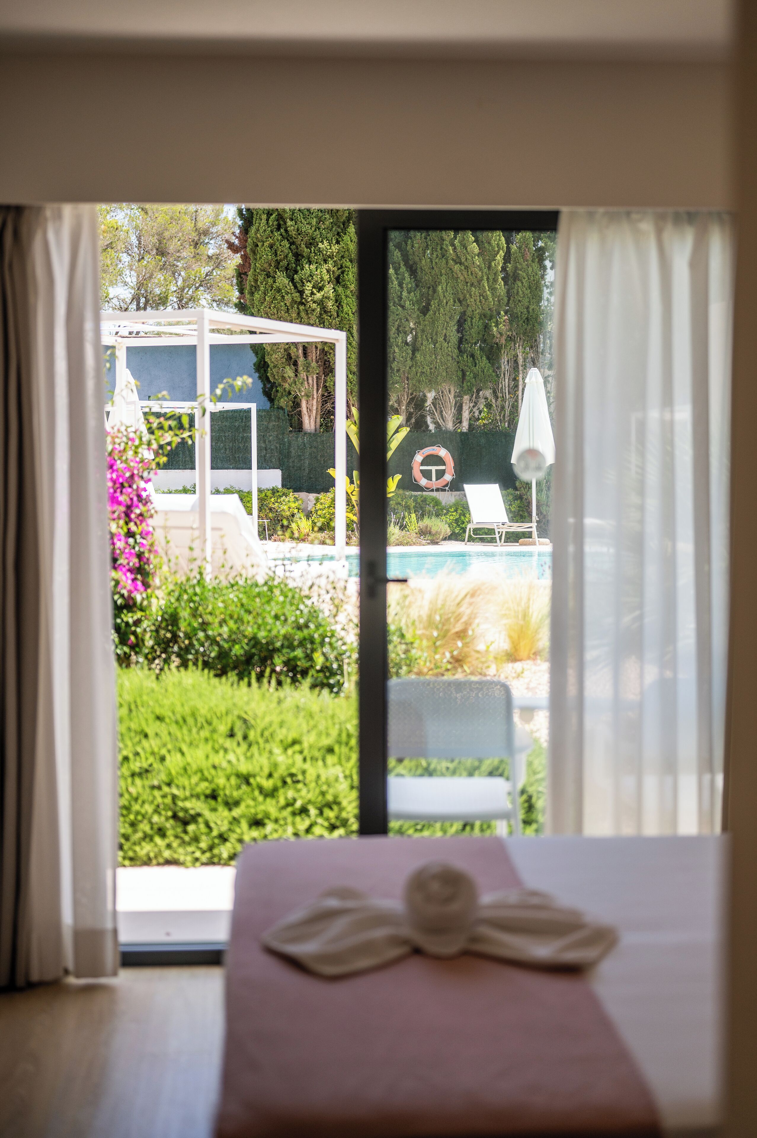 Habitació amb llit, vistes a una piscina i un porxo.